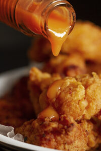 Close-up of Haven Hot Chicken with Nashville-style hot sauce drizzle"
